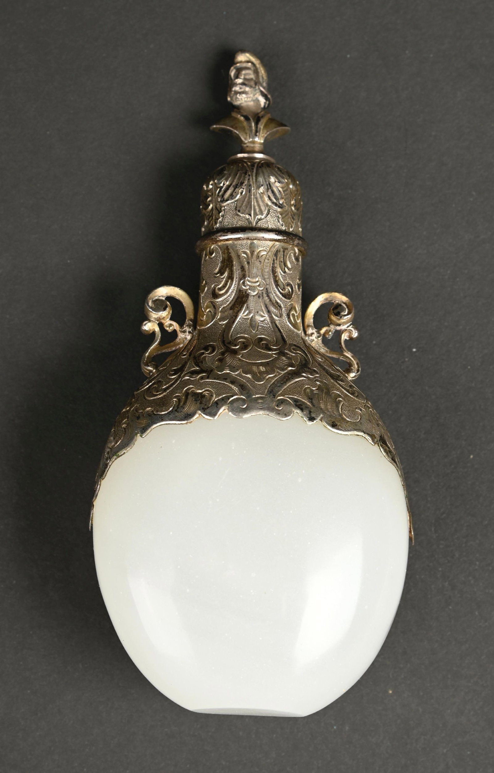 SILVER-MOUNTED GLASS PERFUME BOTTLE: C. 1800s. A wonderful globular white opaline glass bottle with silver ornate decorative mountings, including handles and a hinged lid; the lid top features a French soldier bust decoration. In wonderf