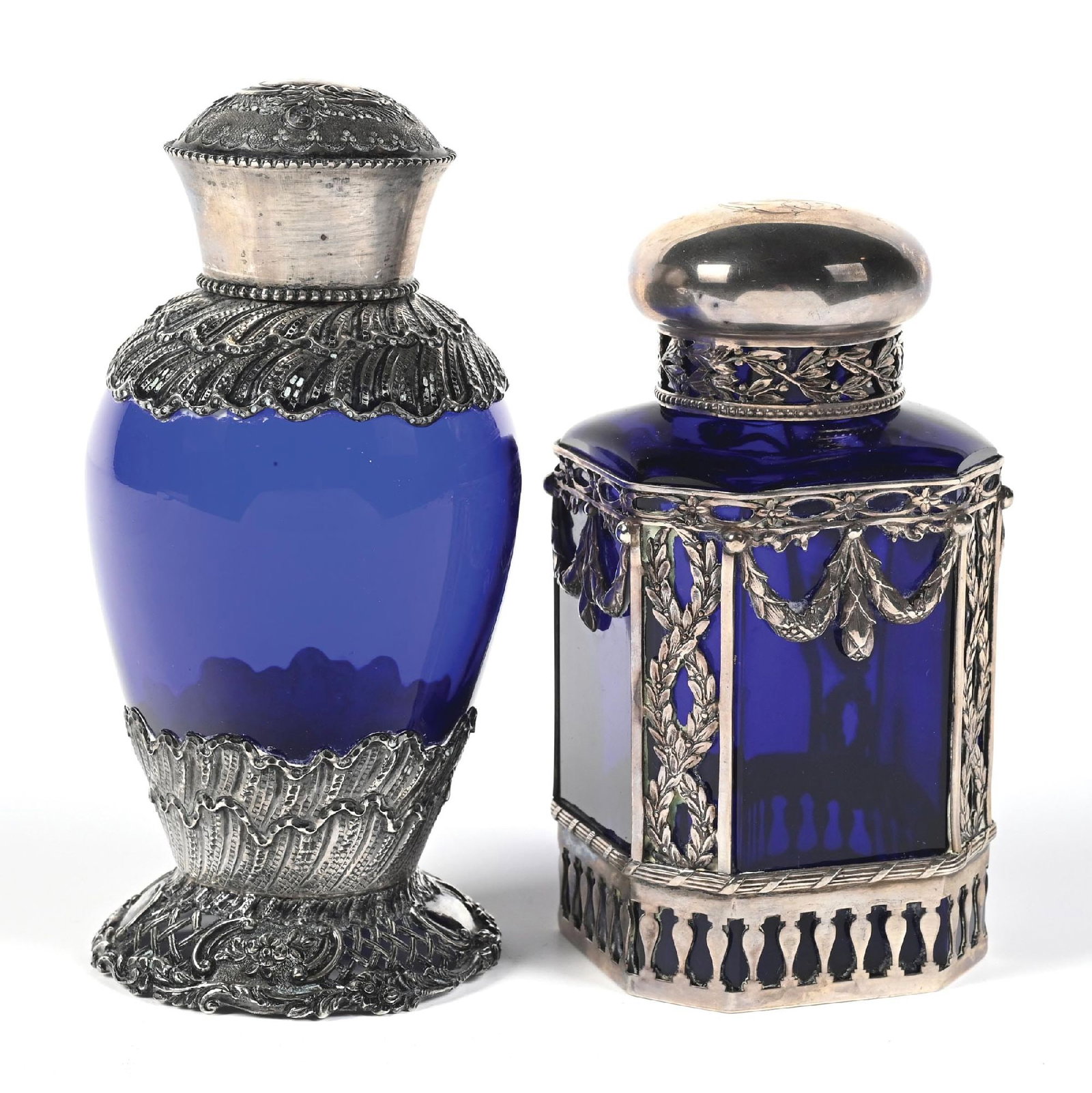 LOT OF 2: COBALT BLUE GLASS WITH STERLING SILVER OVERLAY PERFUME BOTTLES: C. 1900s. (A) A beautiful, ornate cobalt blue glass and Hanau silver (marked 800) overlay perfume bottle. The silver-mounting displays detailed patterns of laurel leaves, garlands, and ribbons in a ne