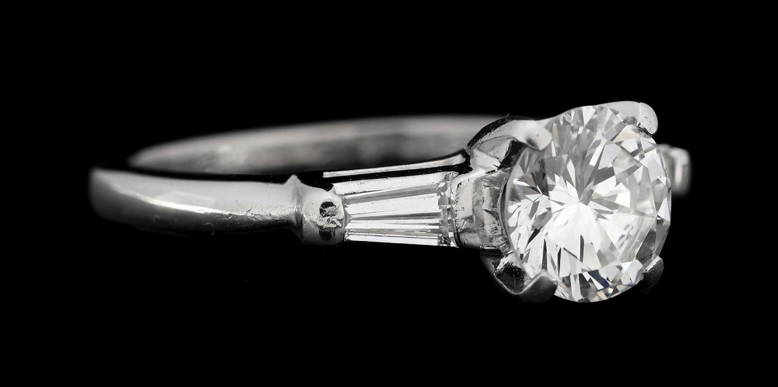 PLATINUM ESTATE 1CT DIAMOND ENGAGEMENT RING: Platinum estate engagement ring set with 1 round brilliant cut natural diamond (1.00ct) graded I, VS2 with 2 tapered baguette cut natural diamonds (0.25ctw). Ring size 5-1/4. Width at top measures 6.5