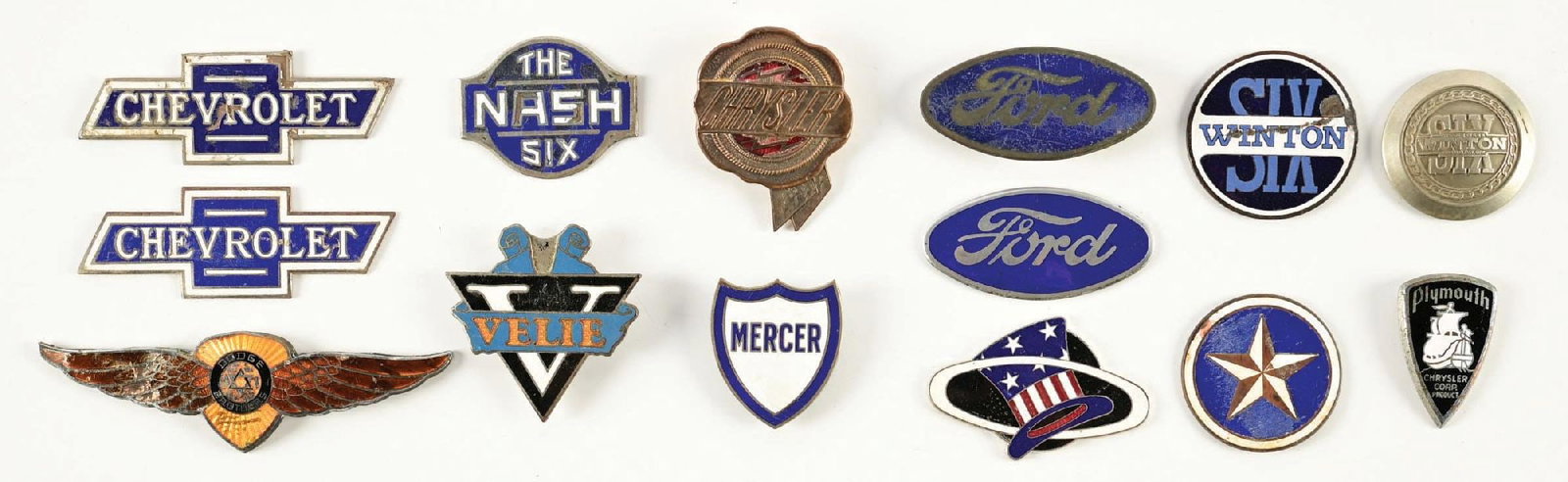 COLLECTION OF 14: ASSORTED AUTOMOTIVE RADIATOR BADGES: Collection Consists Of: Fourteen individual Radiator Badges from various Automobile companies such as Dodge, Ford, Rickenbacker, Plymouth, Velie & others. CONDITION: Each in fair condition showing gen