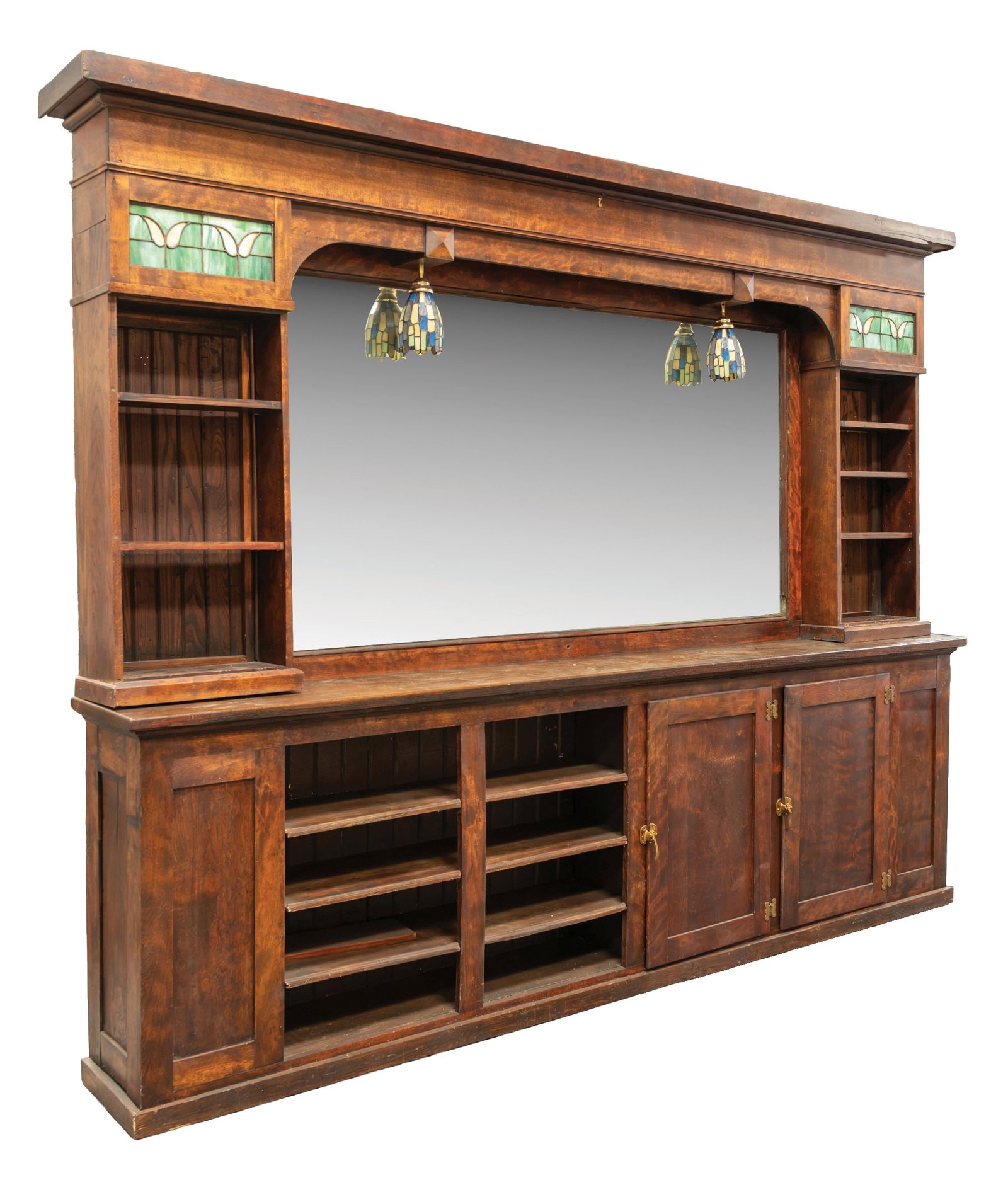 WOODEN BACKBAR WITH MIRROR: C. early 1900s. An impressive 20th century wooden backbar featuring a large central plated glass mirror flanked by open display shelving. The decorative white and green leaded glass panels, substantia