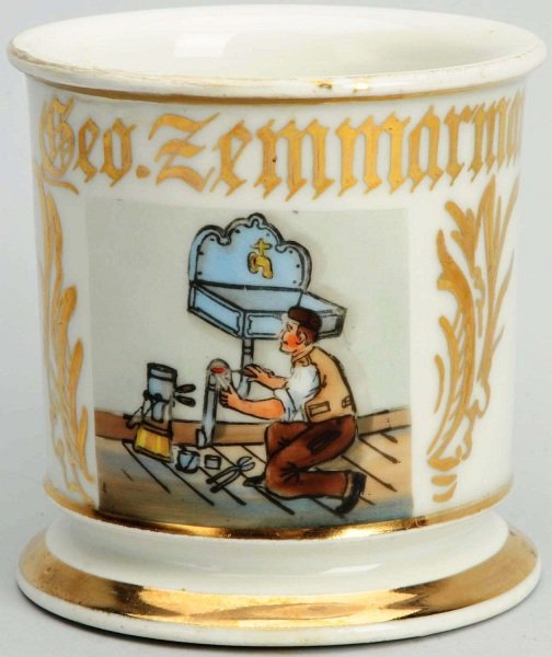Plumber Shaving Mug.: Depicting plumber working on an old-fashioned sink. Has "Geo. Zemmarman" in gold gilt. Minor repair to top rim. No further damages. Condition (Very Good). Size 3 - 3/4" T.