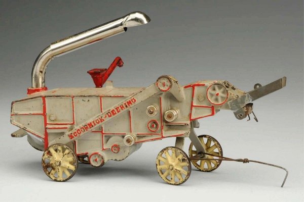 Cast Iron Arcade McCormick-Deering Thresher.: American. Partial Arcade Toy decal on one side. Original pipe in back and chute in front but chute is broken. Toy has some chipping and crazing to the paint overall. Condition (Very Good). Size 10" L.
