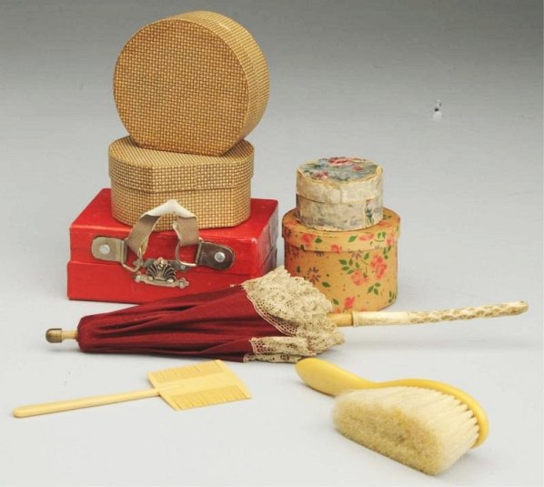 Lot of Antique Doll Accessories.: Red paper-covered cardboard suitcase, maroon silk parasol with ivory handle (one small hole), two hat boxes (one missing handle), paper-covered box (some paper loss), paper box with flower print, cell