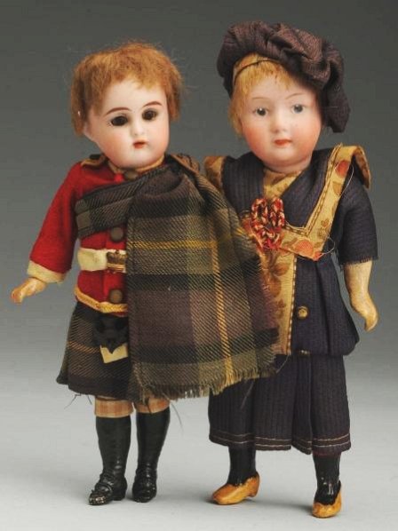 Lot of 2: German Bisque Dolls.: Both with bisque socket heads, original wigs, original five-piece bodies and factory clothing; K & R Scots child has glass eyes; pouty child with intaglio eyes with Gebr. Heubach square mark. Some ove
