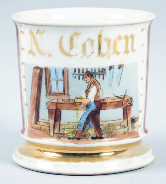 Carpenter Shaving Mug.: Has "N. Cohen" in gold gilt. Moderate loss of gold, with no damages. Depicting old carpenter tools and carpenter. Touched up in a few spots, repair may have been made to handle & repainted. Condition