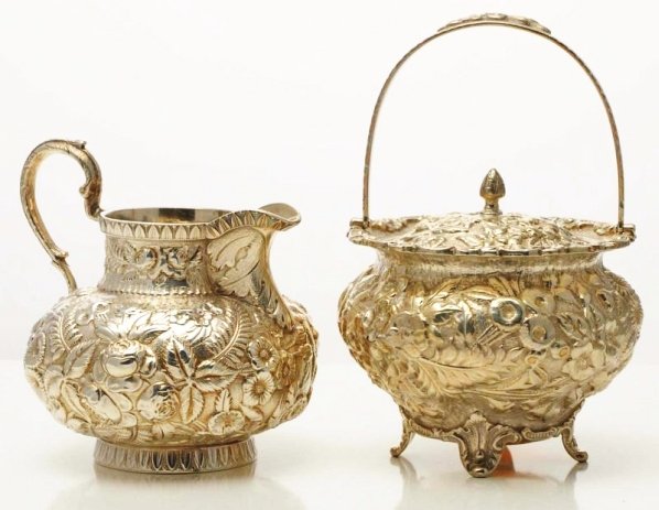 An American Silver Repoussé Cream Jug.: Retailed by Ryland & Rankin, Lynchburg Va. ca. 1900, of bulbous form with a short straight neck, with dense floral chasing and on a flat base; and a covered sugar bowl with a swing handle and on short