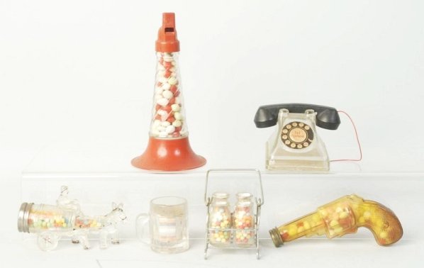 Lot of 5: Glass Candy Containers.: Gun, horn, four milk bottles, man riding a donkey mug and a telephone. No damage or repair. Condition (Excellent). Size Largest: 7" L.