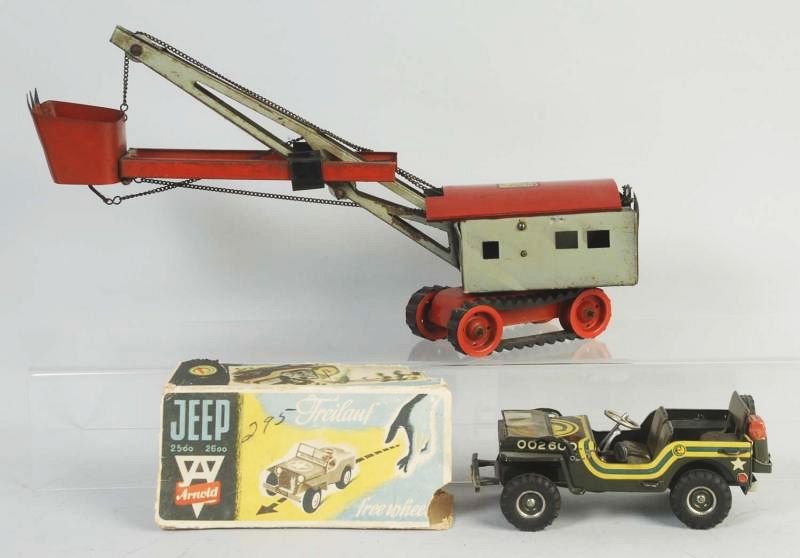 Lot of 2: Tin Toys.: Including a Haking tin steam shovel. Made in Germany. Toy is all original including rubber tracks. Does have some wear and scratching throughout. Second toy is an Arnold Army jeep. Tin wind up does ha