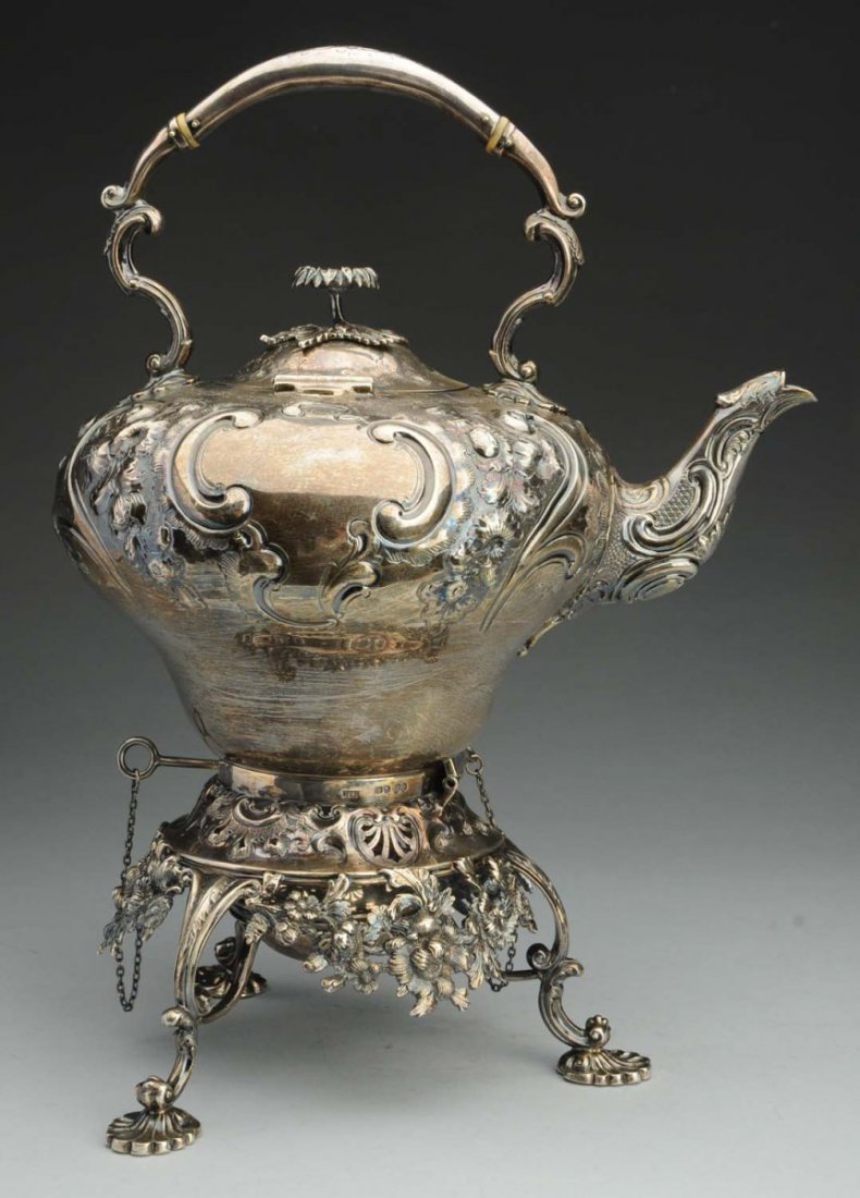 English Sterling Kettle on Stand.: London 1855, Henry Holland, in 18th Century rococo style, the pear shaped body and stand with central burner chased with scrolls and flowers, the sides with two vacant reserves, the base with cast flo