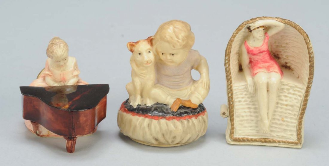 Lot of 3: Celluloid Figural Sewing Tape Measures.: One is a lady playing piano with full spring tape. Second, is a bathing beauty in wicker beach chair with full spring tape. Last is a girl with dog with full spring tape. Condition (Excellent). Size L