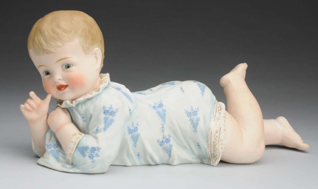 Smiling Piano Baby.: All bisque figurine with exceptionally well molded detail in his smiling face; molded shift with gold trim and painted blue flowers. Nice chubby one! Condition (Excellent). Size 17" L.
