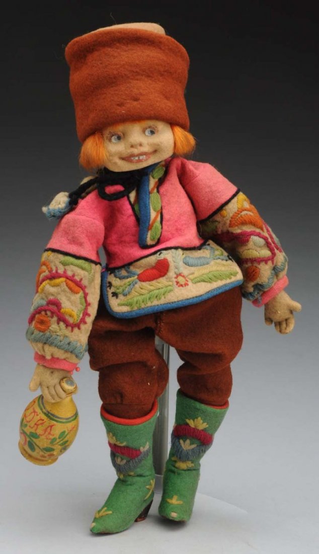 Colorful Lenci Cossack Boy.: Felt face with wide grinning mouth, painted side-glancing eyes, red mohair wig; original felt costume with embroidery trim, boots and cap, carrying a wooden jug (one hand broken at wrist, overall dust