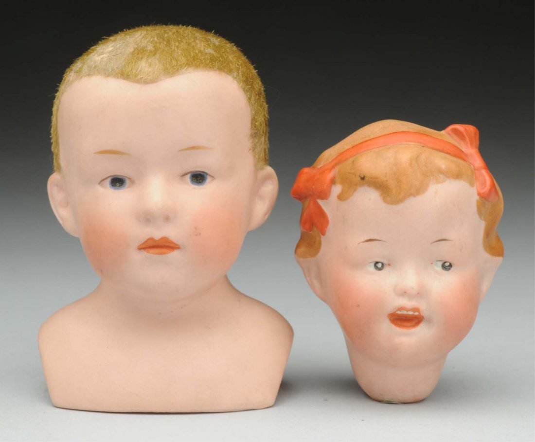 Lot of 2: German Bisque Doll Heads.: Gebr. Heubach 8692 pouty boy, with Heubach sunburst mark, flocked hair, intaglio eyes. Ernst Heubach girl 286 with red bows and sweet character face (several small flakes at neck socket). Two very nic