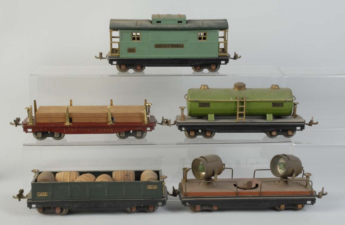 Lot of 5: Pre-war O Gauge Assorted Freights.: No.815 pea green tank car. Is complete and all original. Has some rust on axles. No.820 searchlight car missing a coupler has rust on remaining coupler and axles. No.812 gondola with six barrels. Need