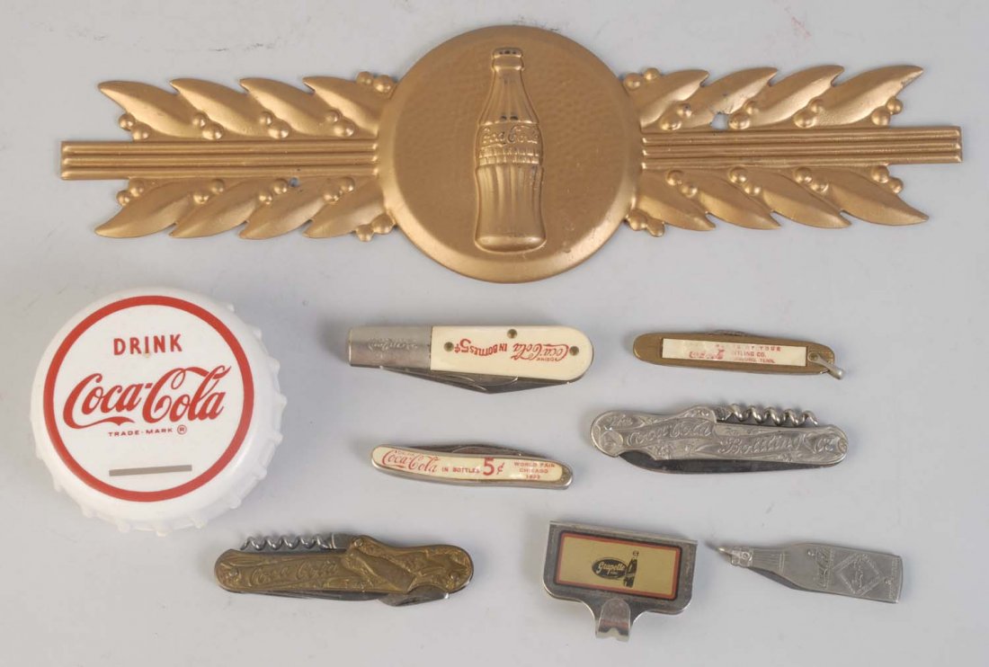 Lot of Small Coca-Cola Pieces.: Most of the knives are a later issues or reproductions. The crest is a reproduction. Condition (Excellent). Size Largest: 12 - 1/2" L.
