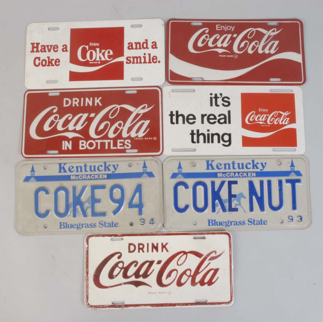 Assorted Coca-Cola License Plates.: Seven tags with light to moderate overall wear. Dates range from the 60s - 90s. Condition (Excellent). Size Each: 12" x 6".