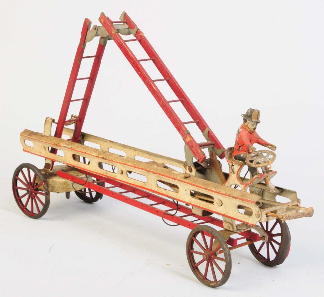 Pressed Steel Wind-up American Fire Ladder Truck.: Cast iron rider in front is original but has several cracks in his back. Not marked but probably Converse. Has a couple of original wooden ladders. Two joined at the top and one laying at the bottom. 