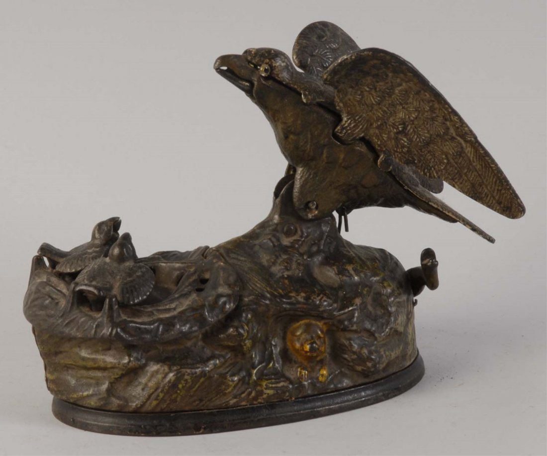 Eagle And Eaglets Mechanical Bank.: Manufactured by J&E Stevens Company and is in working condition. The bank depicts a mother eagle with two eaglets in their nest. The bank is painted in light brown color, and it is very well preserved