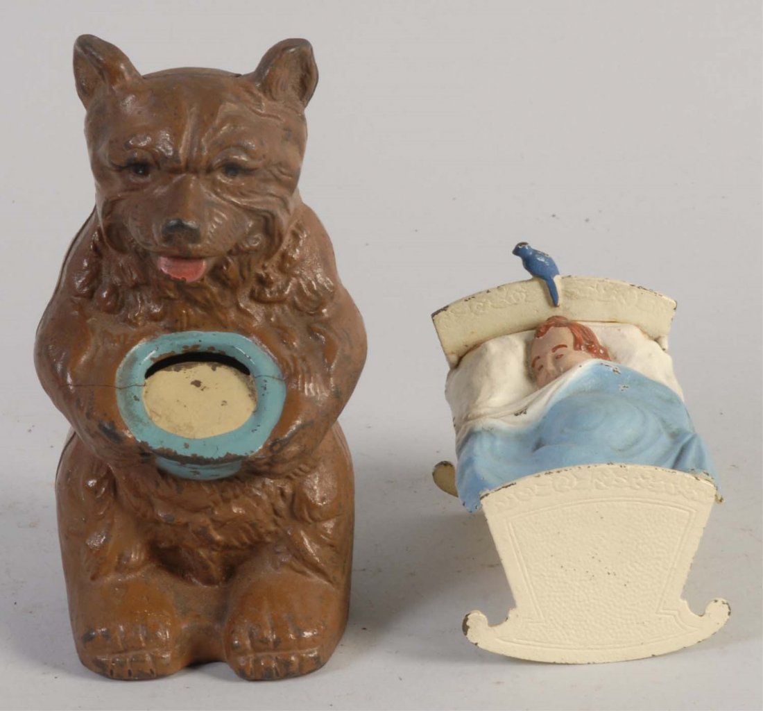 Lot of 2: Cast Iron Still Banks.: Includes a Honey bear, and a Baby in cradle bank. Both banks have some paint chips and scratches throughout, and they are painted in brown, blue, and tan colors. The banks are preserved excellently. C