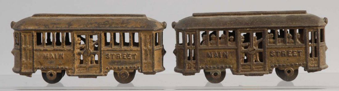 Lot of 2: Cast Iron Trains.: One of the trains is painted in dark yellow and the other is painted brown. There is significant paint loss and paint chips throughout. The trains are embossed on both of their sides with "Main Street