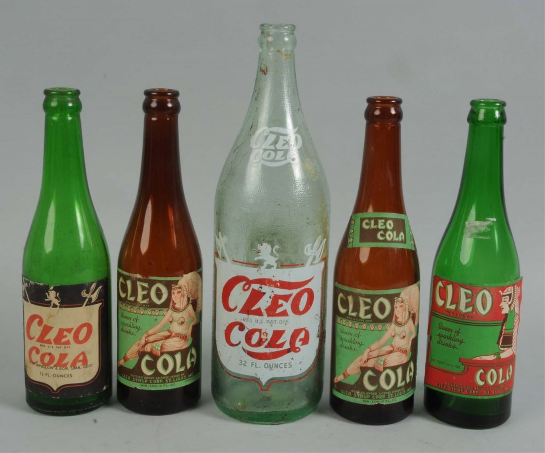 Lot of 5: Assorted Cleo Cola Bottles.: Includes four paper labeled bottles and one color labeled bottle. Moderate overall wear and paper tears. Nice group with a variety of labels you rarely see. Condition (Very Good). Size Largest: 12" T.