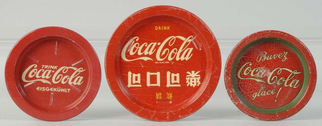 Lot of 3: Assorted Coca-Cola Coasters.: German, French, and Asian, 1930s-50s.Crazing and wear on two, with less wear on the German coaster. Condition (Very Good - Excellent). Size Largest: 4 - 1/2" Dia.