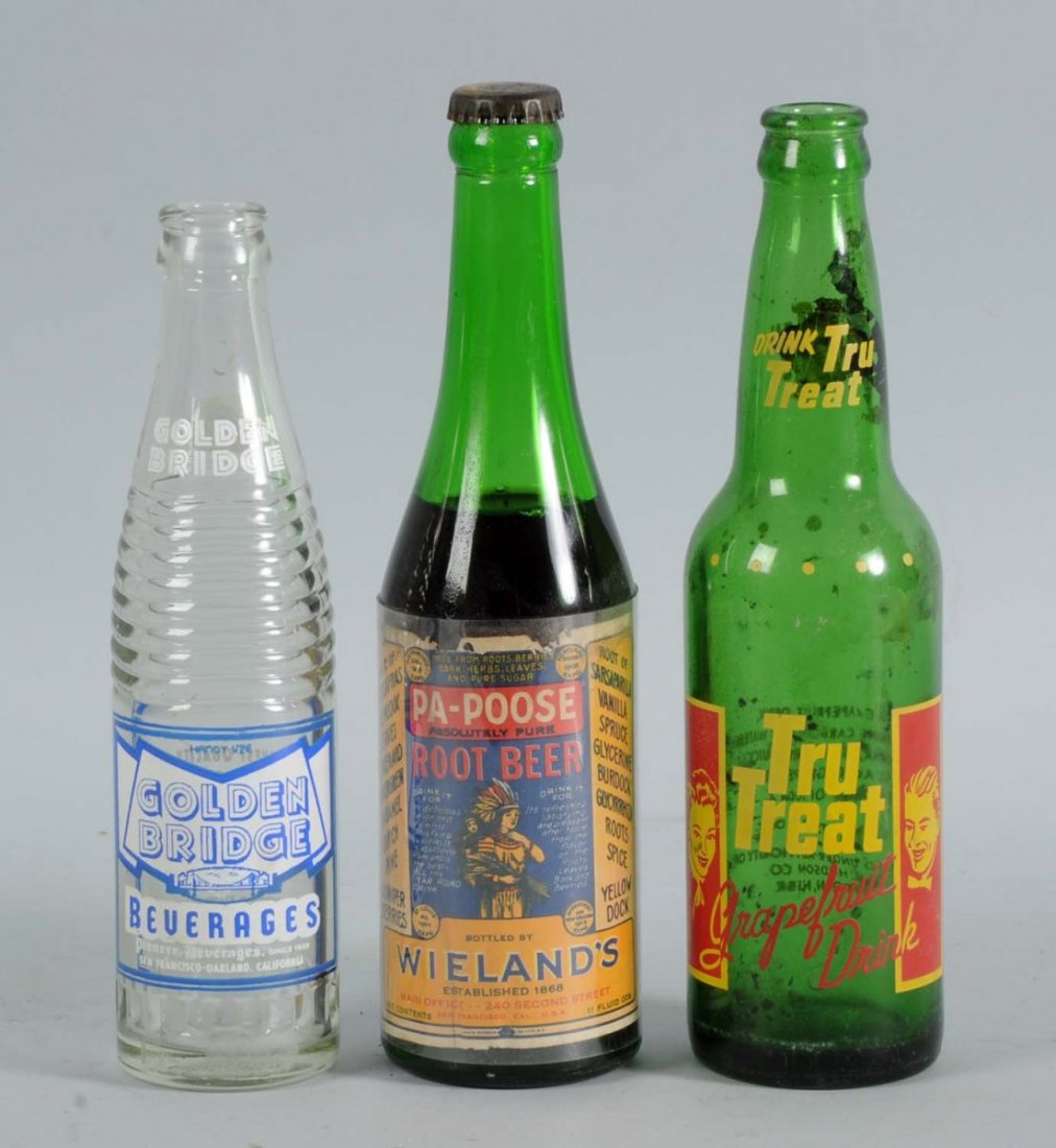 Lot of 3: Assorted Soda Bottles.: This lot includes a Weiland's Pa-poose root beer bottle with the paper label, a Trutreat bottle, and a Golden Bridge bottle. Condition (Very Good). Size Largest : 9 -1/2" L.