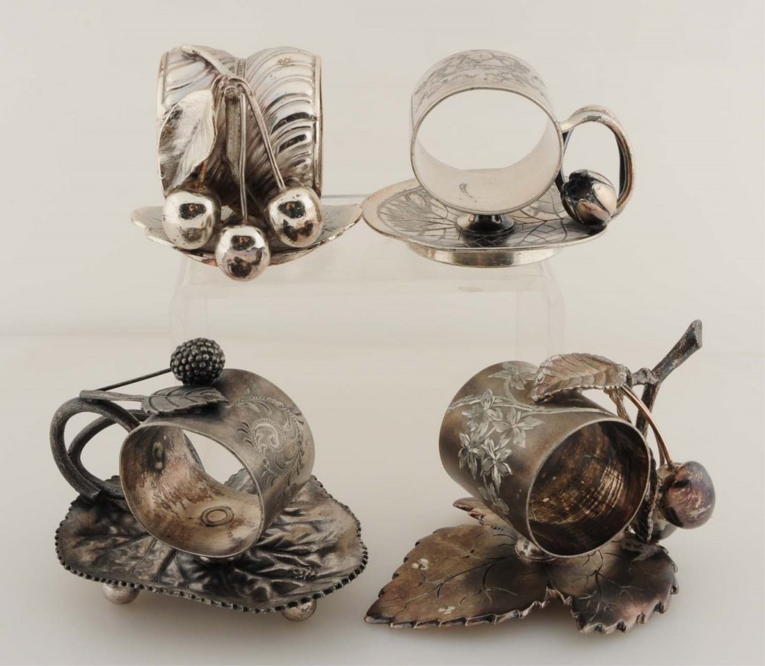 Lot of 4: Figural Napkin Rings.: Lot includes: a napkin holder on a lily pad with a lily bud and finger hold, base is marked 'Rogers & Bros. No. 168'. An unusual holder adorned by 3 cherries and a leaf, with a base also shaped like a