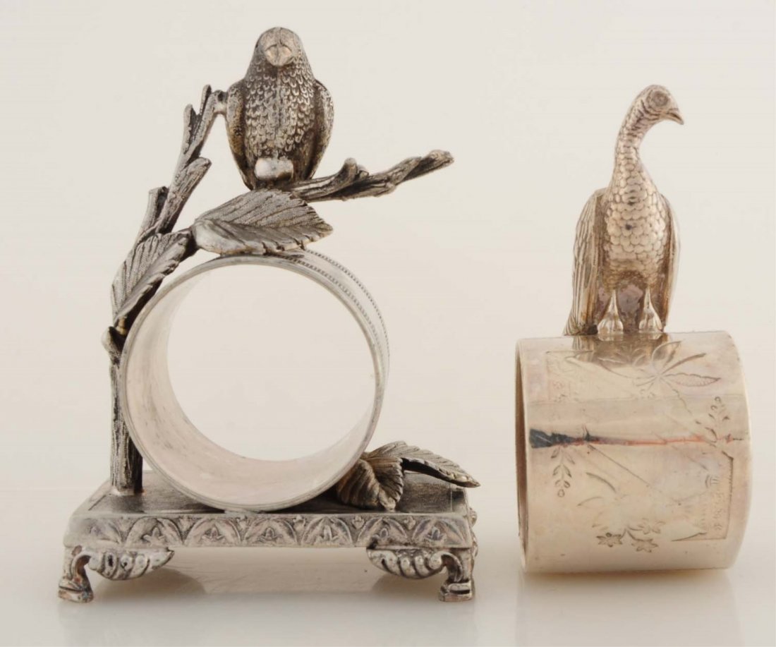 Lot of 2: Figural Napkin Rings.: Lot includes: a napkin ring in which a vulture hovers on a leafy branch over napkin holder. Footed rectangular base is marked 'Toronto S. P. Company. No. 028'. And a napkin holder with a peacock on to