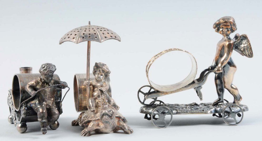 Lot of 3: Figural Napkin Rings.: The first napkin ring in the lot depicts a draped cherub wearing a hat, riding a turtle, and holding an umbrella toothpick holder. Half of the reins to the turtle have become unsoldered. Behind the ch