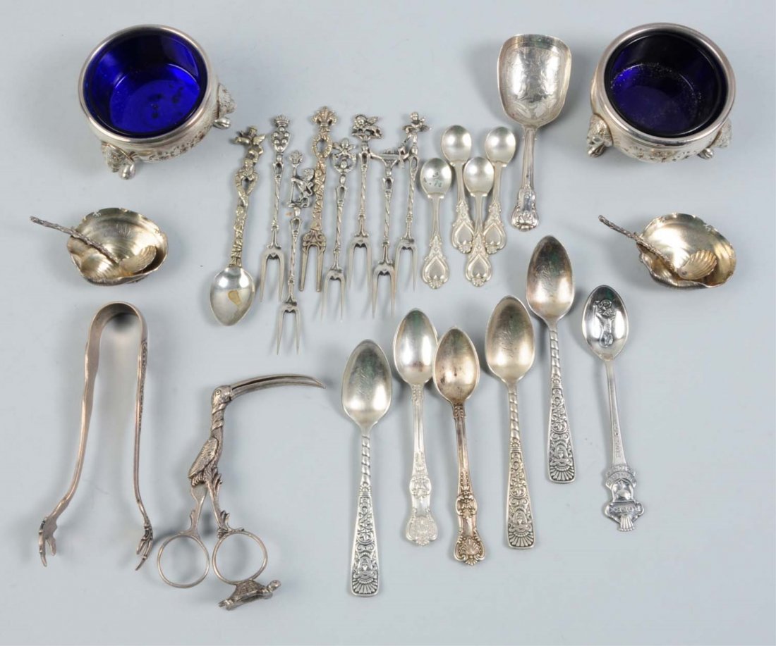 Group of Sterling Articles.: Includes two salt cellars with glass liners, two small shell dishes, several cocktail forks, a pair of sugar tongs, a pair of stork ribbon scissors, and several demitasse spoons. Weight: 10 ozt.