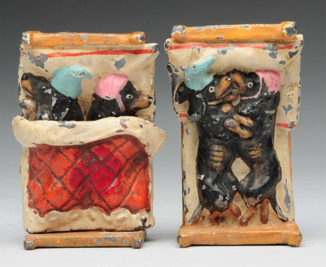Pair of Beds with 2 Dachshunds in Beds.: Circa 1900. Made of metal. One shows them facing opposite directions and the other getting intimate. Missing one blanket. Some paint chipping. Condition (Good). Size 2" L.