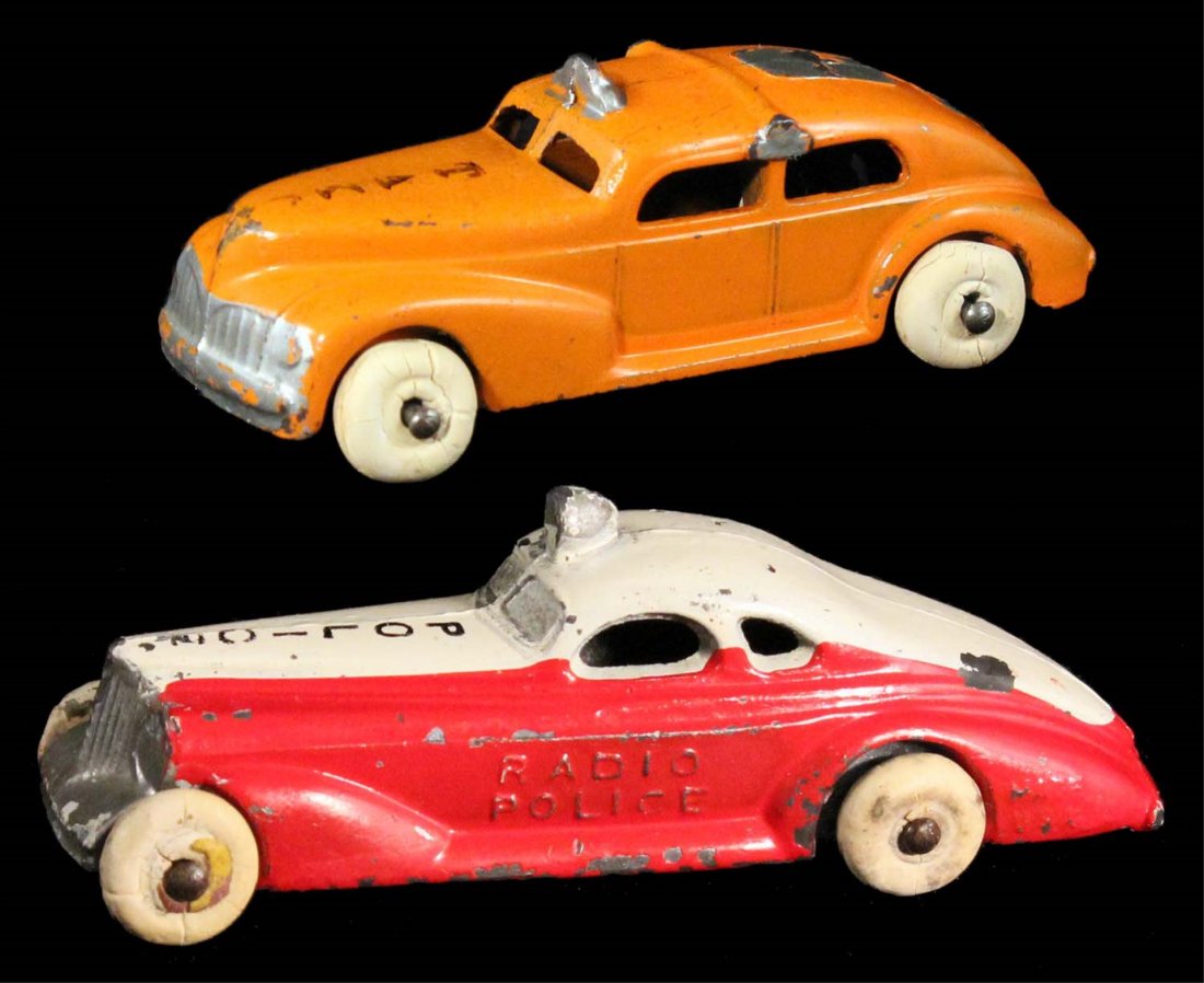Lot of 2: Slush Mold Cars.: CIrca 1930s, Barclay. Painted cast metal with white rubber tires. Taxi is orange with silver trim, and Police Radio Patrol is two-tone red and white with scattered chips. Condition (C7 Very Good - C8 
