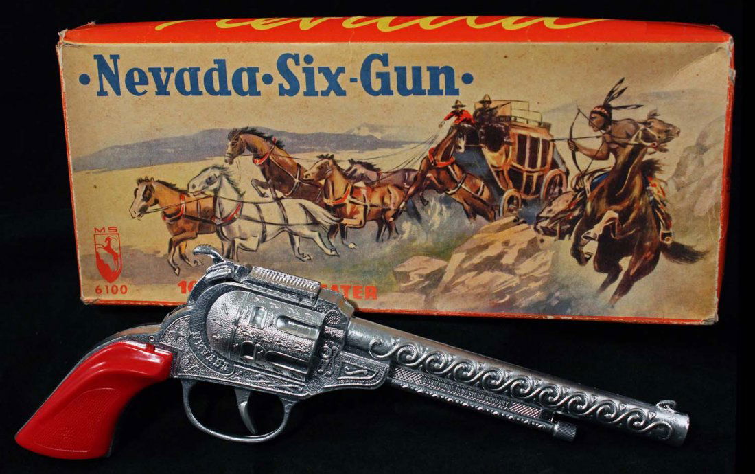Nevada Six Gun Cap Pistol.: No. 6100, in box, Western Germany. Silver finish with red plastic grips. 100 shot repeater. Clear tape on one end of box. Condition (C7.5 Very Good - C9.5 Near Mint Plus).