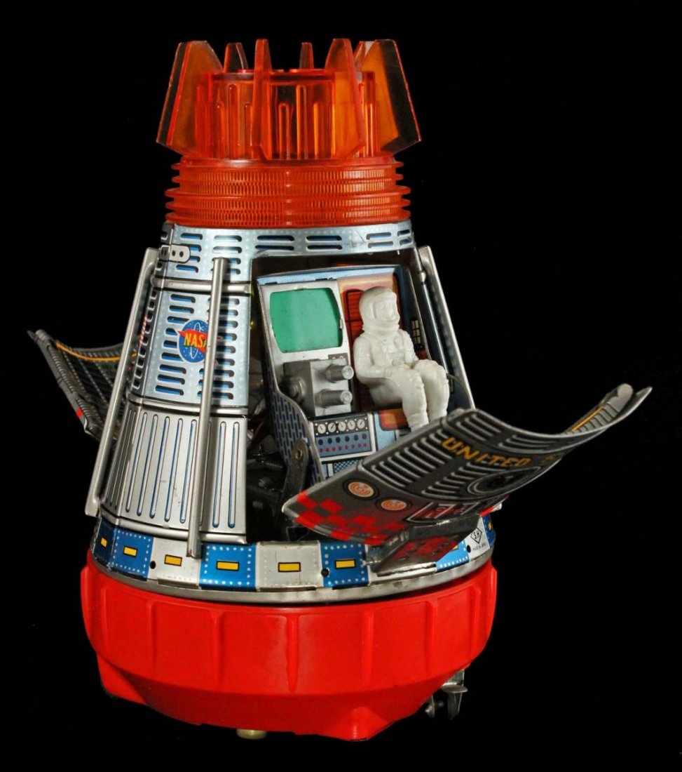 Japanese Tin Space Capsule.: Circa 1963, S.H. Horikawa, Japan. Lithographed tin battery-operated toy with opening panels, blinking lights and spinning action. Reveals seated spaceman. Has NASA logos in graphics. Metal hinges scuf