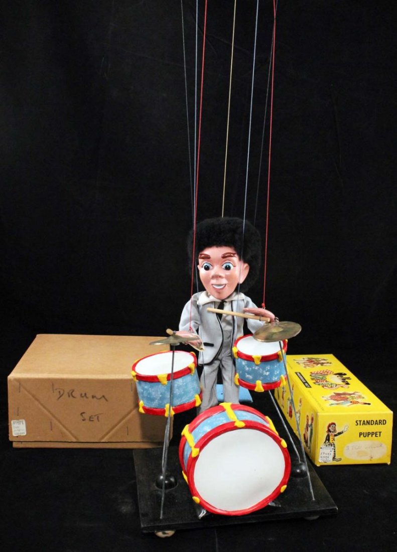 Unlicensed Beatles Pop Singer No. 3 Marionette.: Drum player marionette and drum set in boxes; circa 1964, Pelham Puppets, England. Figure has composition head, hands, and feet; with wood drum sticks and flocked 'mop-top' hair, dressed in a light gr