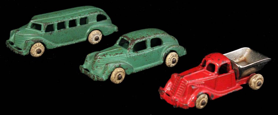 Lot of 3: Small Hubley Cast Iron Vehicles.: Circa 1920s. Painted cast iron with white rubber tires. Includes coach bus, four-door sedan, and a dump truck with a nickel bed. Condition (C6.5 Good Plus - C8 Excellent).