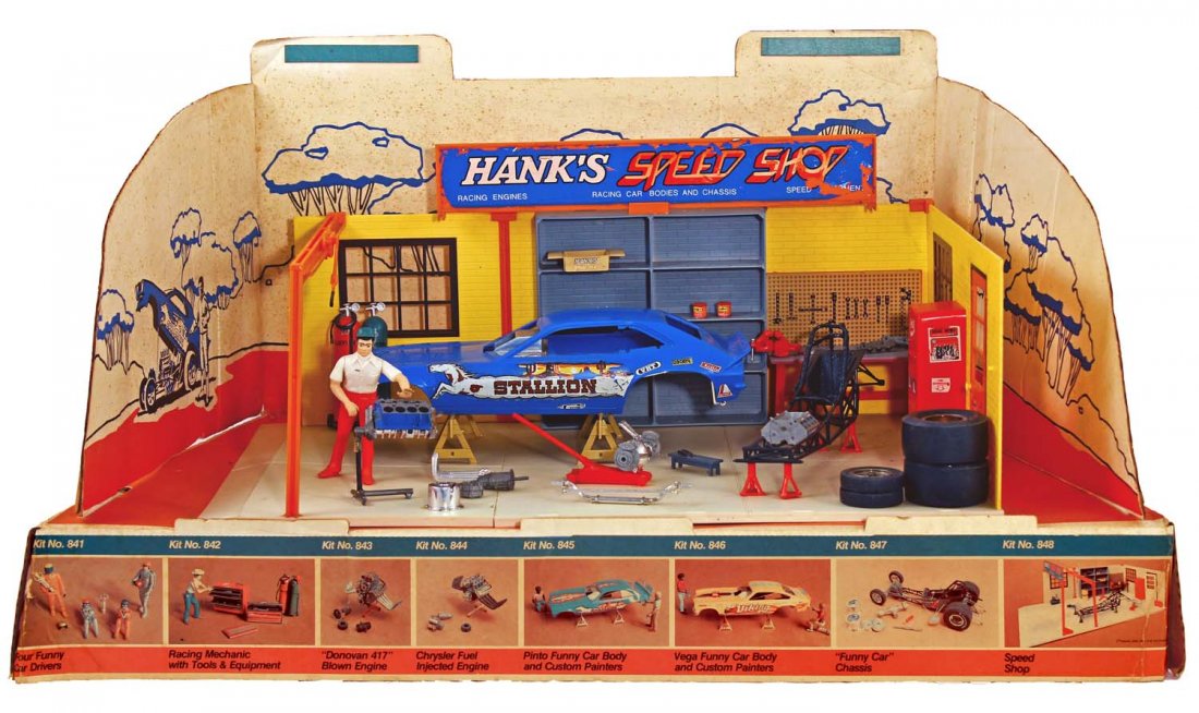 Aurora Racing Scenes Hanks Speed Shop Display.: Circa 1973, Aurora. Printed cardboard base contains six factory–assembled and painted kits from the "Racing Scenes" Funny Car model kit series; cardboard is lightly soiled; some decal flaking, espec