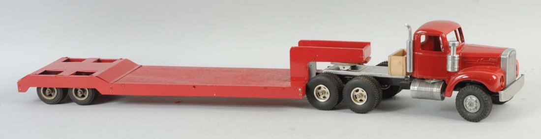 Pressed Steel Red Mack Truck.: The truck is a longer version of the flatbed truck. There are no visible scratches or paint chips throughout, and the front of the truck is missing its headlights.