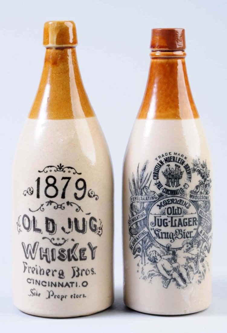 Lot of 2: Stoneware Beverage Bottles.: The first bottle is for 1879 Jug Whiskey from Freiberg Brothers Cincinnati, OH. The second bottle is for Moerlein's Old Jug Lager from Cincinnati, OH. Condition (Very Good). Size Largest: 11" T.