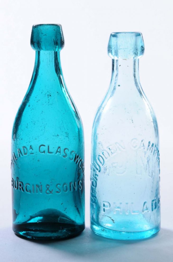 Lot of 2: Early Beer Bottles - Philadelphia.: This lot includes: a light turquoise bottle from McCrudden Campbell and Co. and a turquoise bottle from Burgin and Sons. Both have a light contact scratching. Condition (Very Good Plus). Size Each: 7"