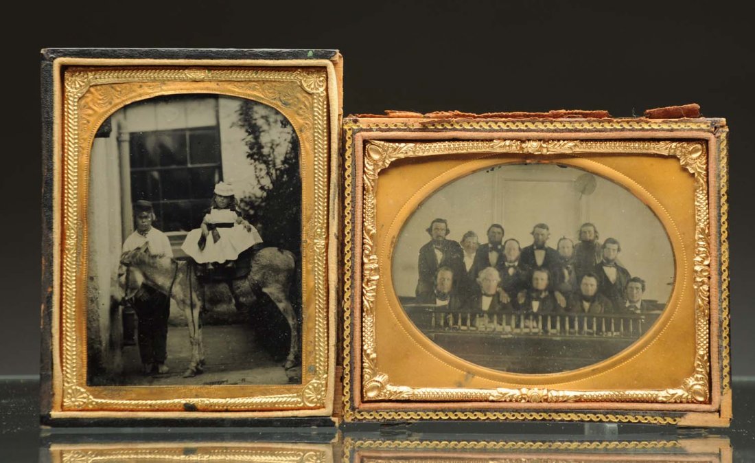 Lot of 2: Ambrotypes.: 1/4 plate. First ambrotype is an outdoor scene of a child riding a donkey with a boy and a horse in the background, clear image in half of a leather case. Second ambrotype is of a group of 13 men sitt