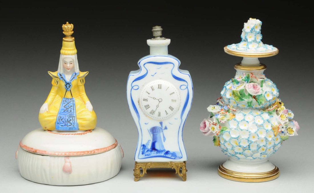 Lot of 3: Perfume Bottles: First: Embossed flowers marked JP on bottom. Minor loss to flowers. Second: Delft milk glass with embossed clock and windmill. Third: Porcelain covered dish with a perfume top with Asian figure marked