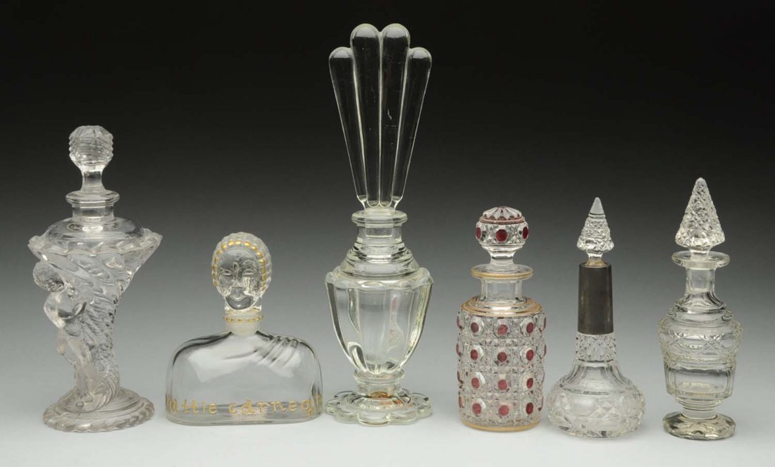 Lot of 6: Clear Glass Perfume Bottles: One marked Hattie Carnegie. One with cherub. One with sterling silver top and cut glass. One art deco form. Two with cut glass. Condition Excellent Size Largest: 7" T.