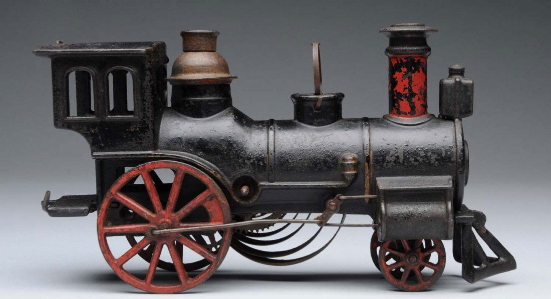 Early Ives Clockwork Cast Iron Engine.: American steam-type style with iron wheels and American-style cow catcher on front. Patented 1880. It is missing the original bell and has some pitting and paint loss. Condition (Very Good). CORRECTIO