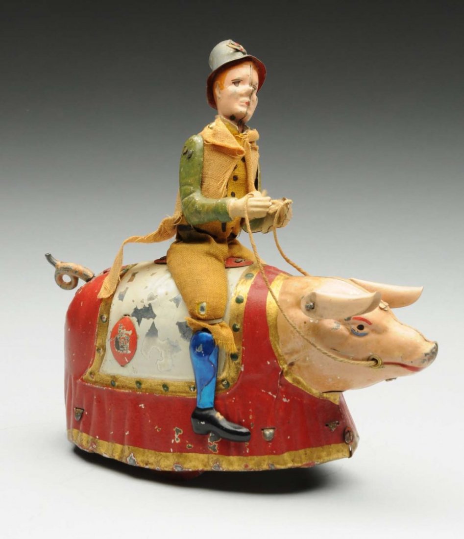 German Tin Litho Wind-Up Paddy and the Pig Toy.: Toy depicts Irishman riding pig. Pig has original ears and tail. Original cloth to figure is soiled and faded. Some paint loss to the sides of the pig, and some scratching to the front. Condition (Ver