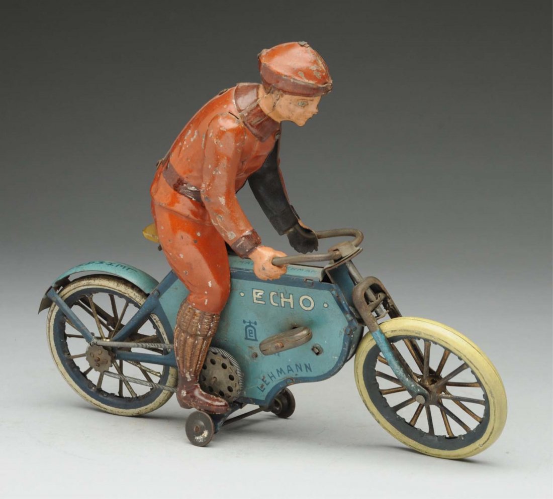 German Lehmann Tin Litho Wind-up Echo Motorcycle.: Original guide wheels marked "Lehmann" with bell mark on sides. Original arms on driver. Moderate litho loss and wear to figure. Condition (Very Good - Excellent). Size 9" L.