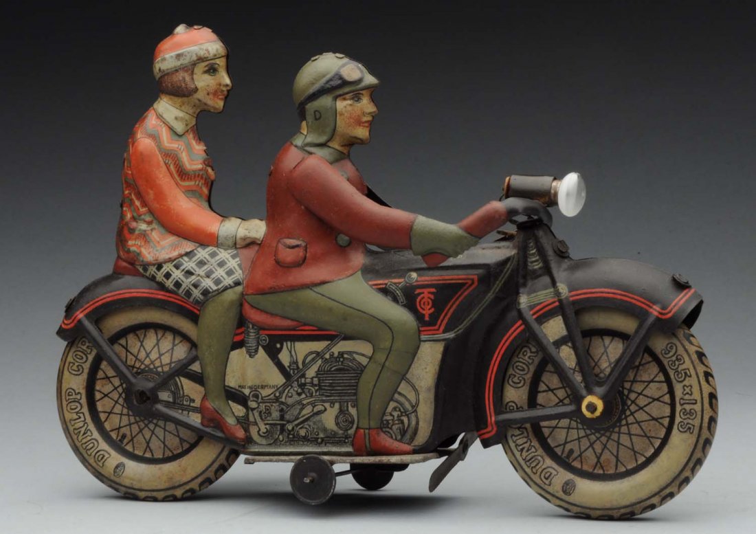 German Tippco Tin Litho Wind - Up Motorcycle Toy.: Unusual Bike with rider and lady passenger. Electric headlight. Marked "Made in Germany" on sides and "Dunlap Cord" on wheels. Original bottom wheels. Areas of repaint to the lithography on areas of d