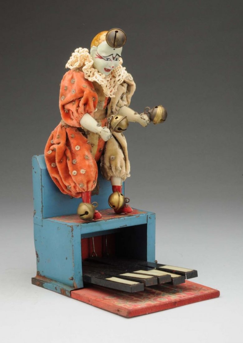 Early French V.B. Clown Toy.: Interesting handpainted toy. Clown sits on top of a wooden piano, and arms, legs and head are moved by pushing the levers on the base. Arms and legs are holding bells. Looks to have original clothing.